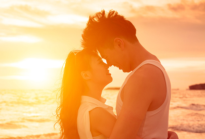 Man and women showing intimacy on a beach with sunset
