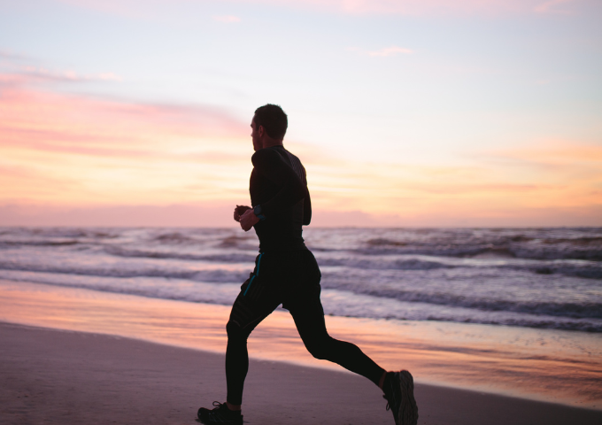 Silhouette of man running along the beach at sunrise